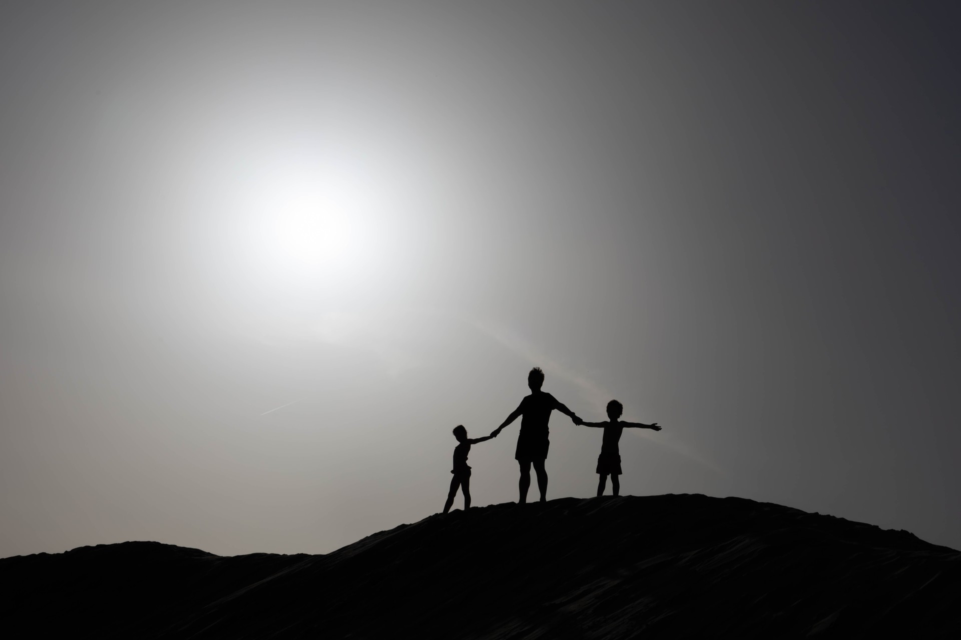 Imagen de una familia sobre una duna en un contraluz.